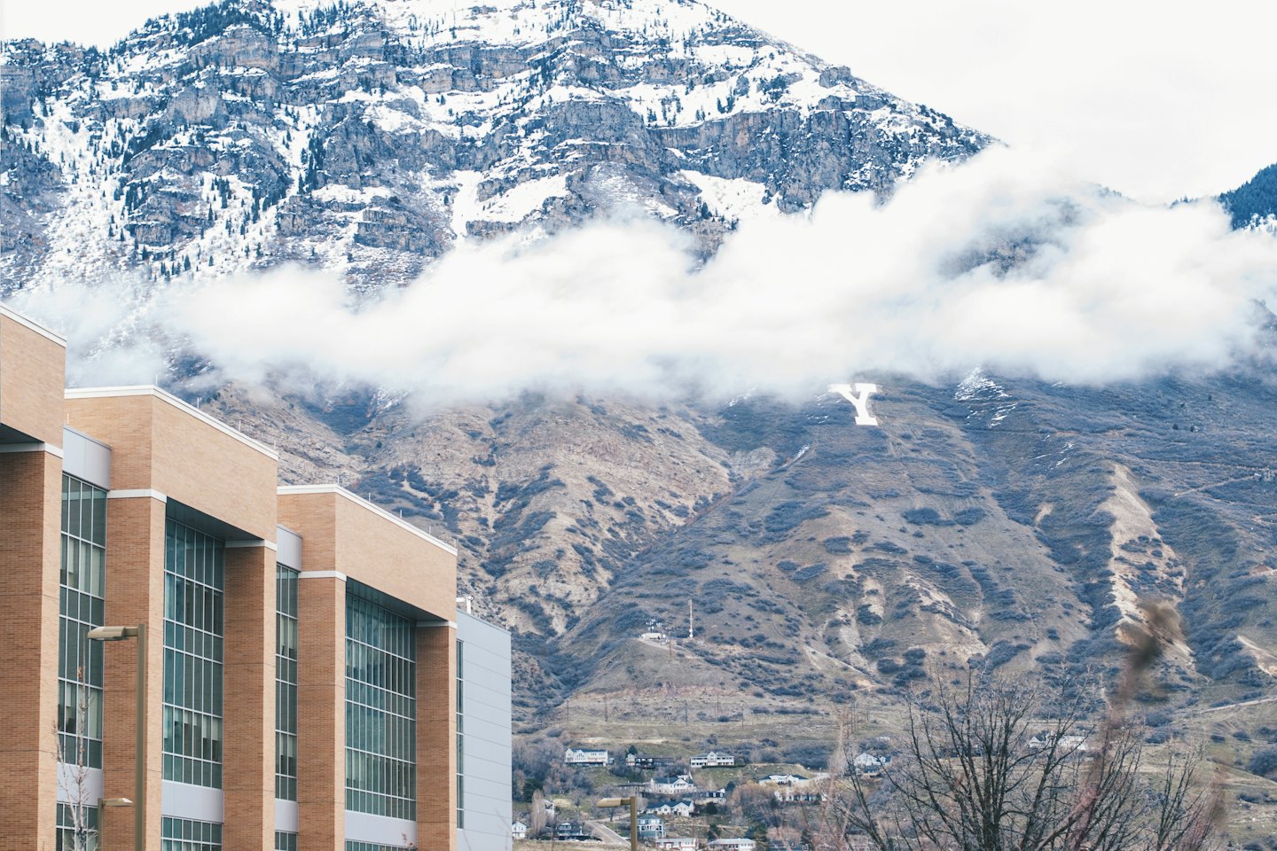 Modern brick and glass building set against snow-capped mountains.