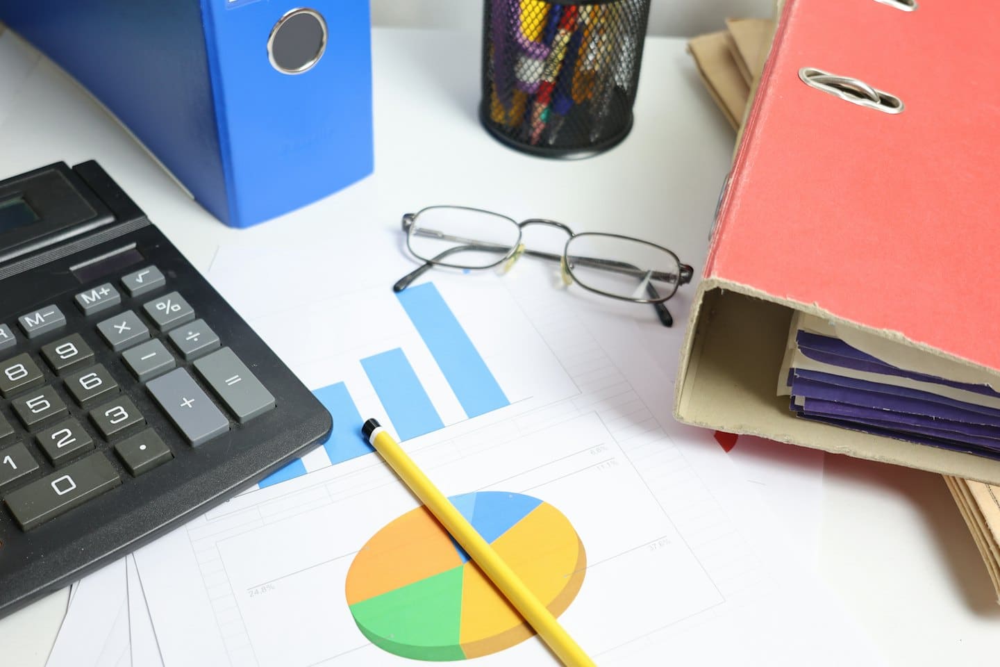 Office desk with papers, binders, calculator, and pencil.
